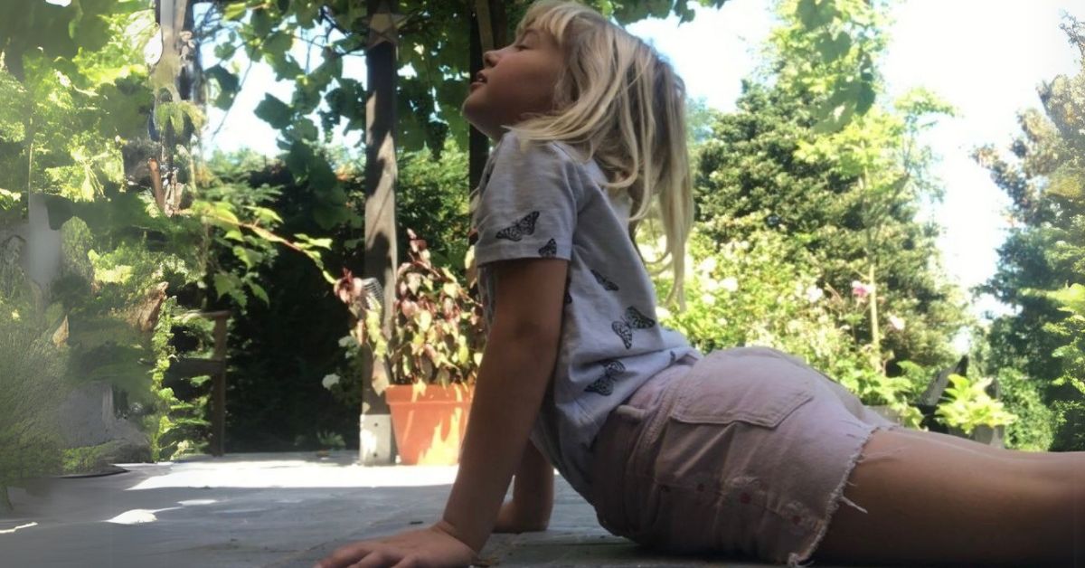 Kind die de zonnegroet doet buiten in de tuin